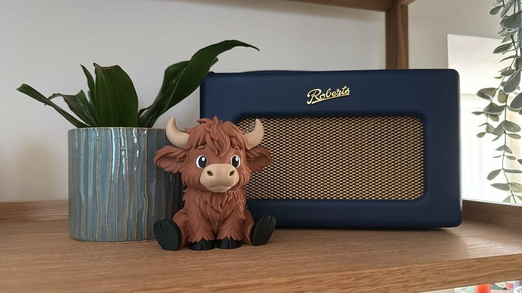 Highland Cow Figurine, main photo of the highland cow on a shelf next to a radio
